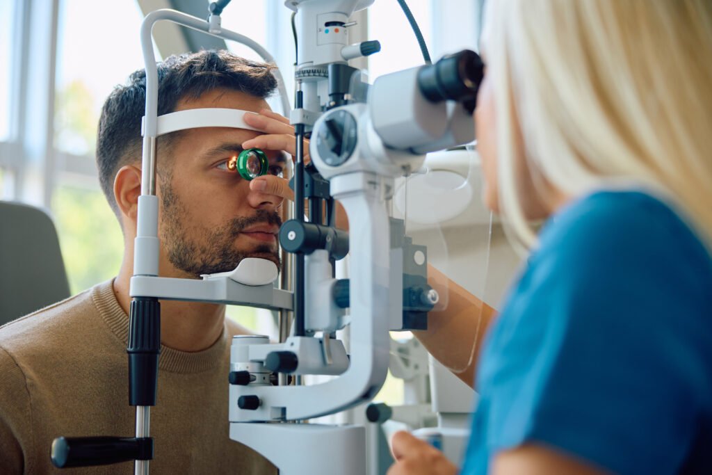 Man undergoing a slit lamp eye examination with an ophthalmologist using a handheld lens
