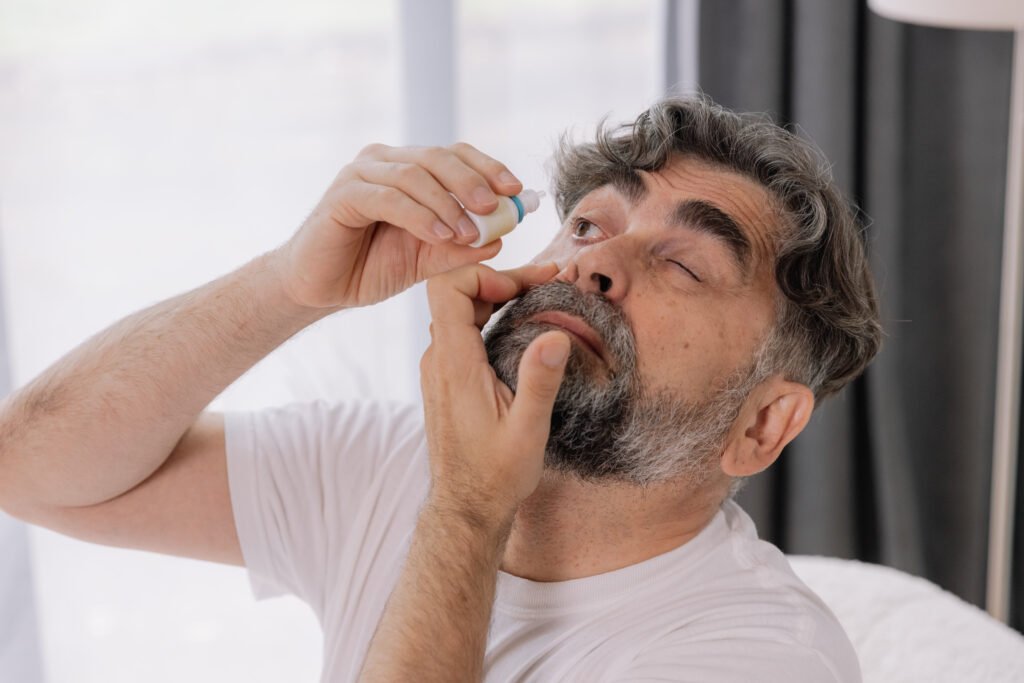 Close-up photo of an older gray-faced man who drips eye drops wi thumbnail